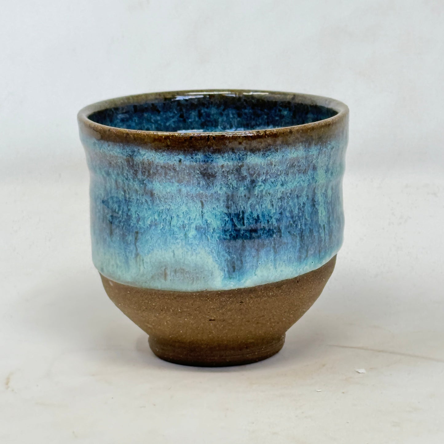 Ceramic cup with blue and brown glaze on a white background