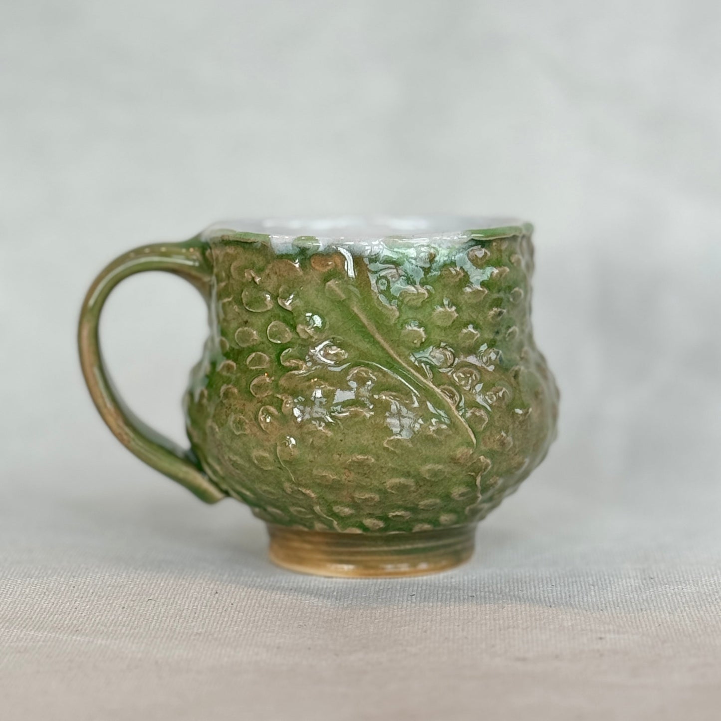 Green ceramic mug with textured design on a light gray background
