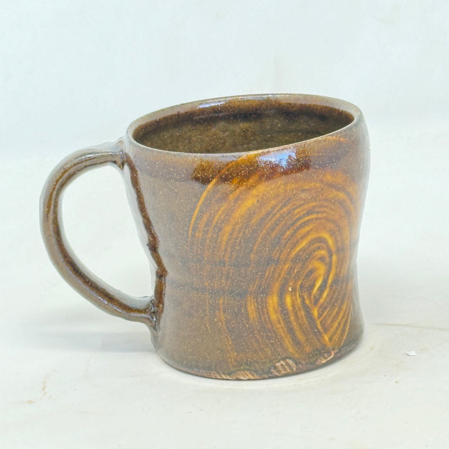 Ceramic mug with brown and beige glaze on a white background