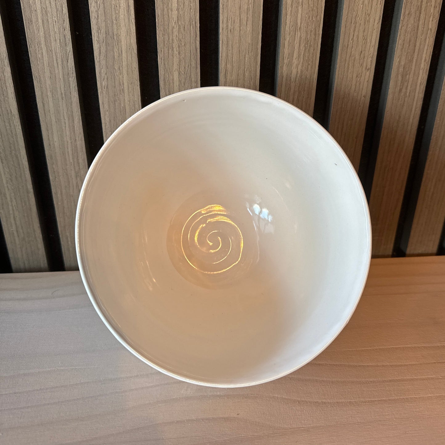 White ceramic bowl with a swirl pattern on a wooden surface