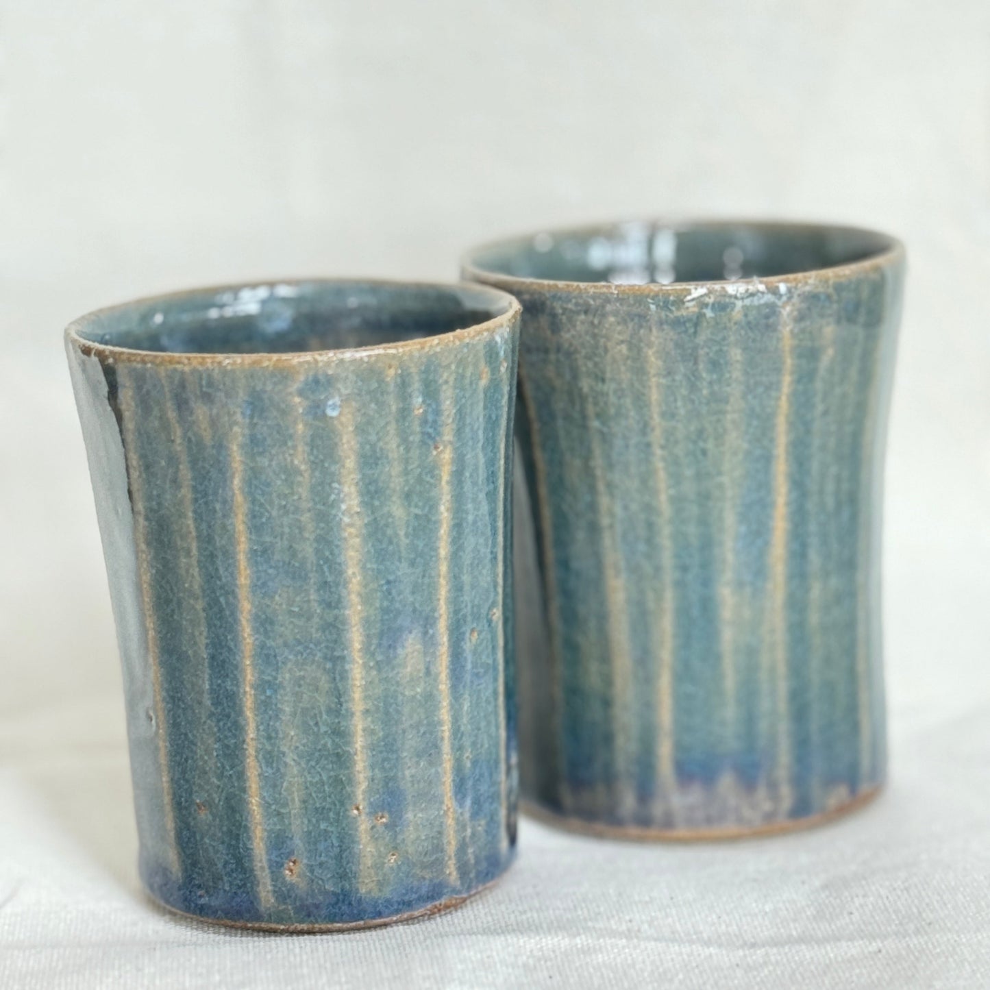 Two blue ceramic cups with a textured surface on a white background