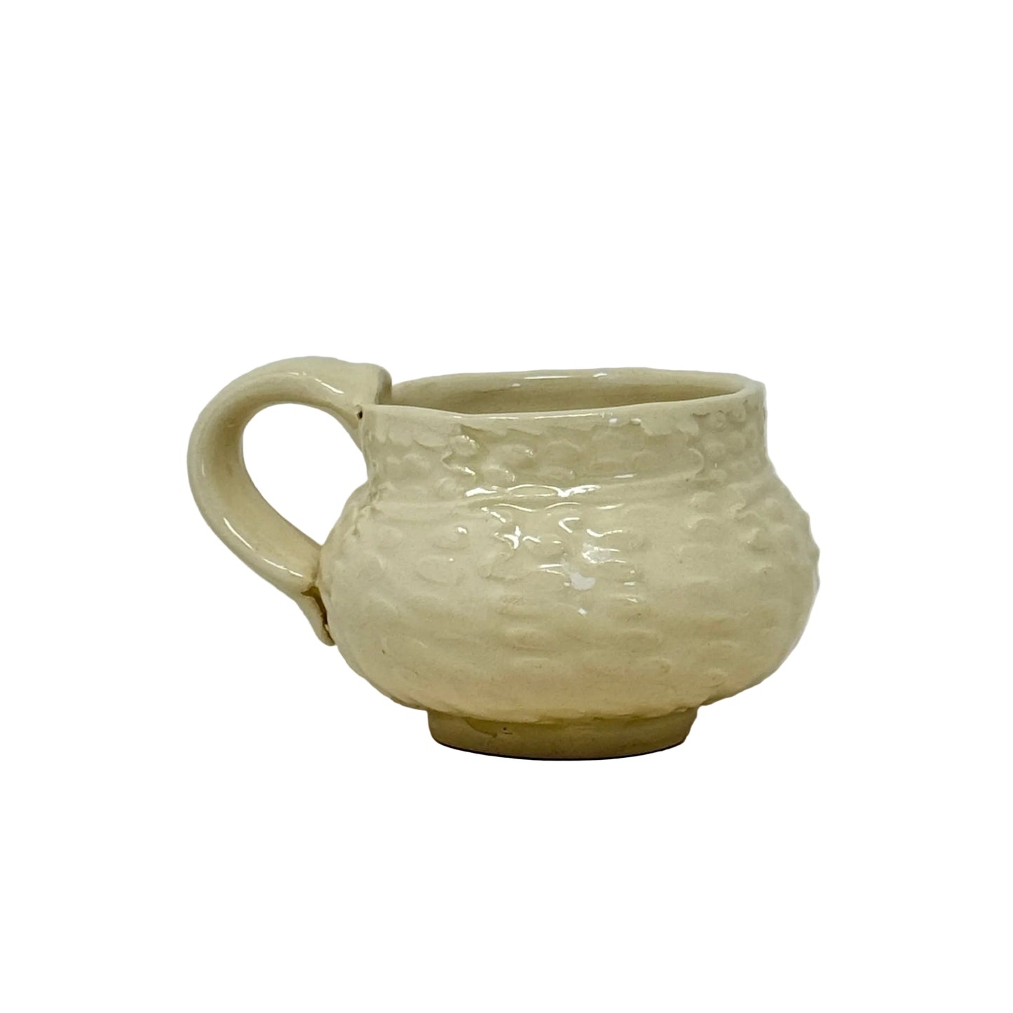 Cream-colored ceramic cup with textured surface on a white background