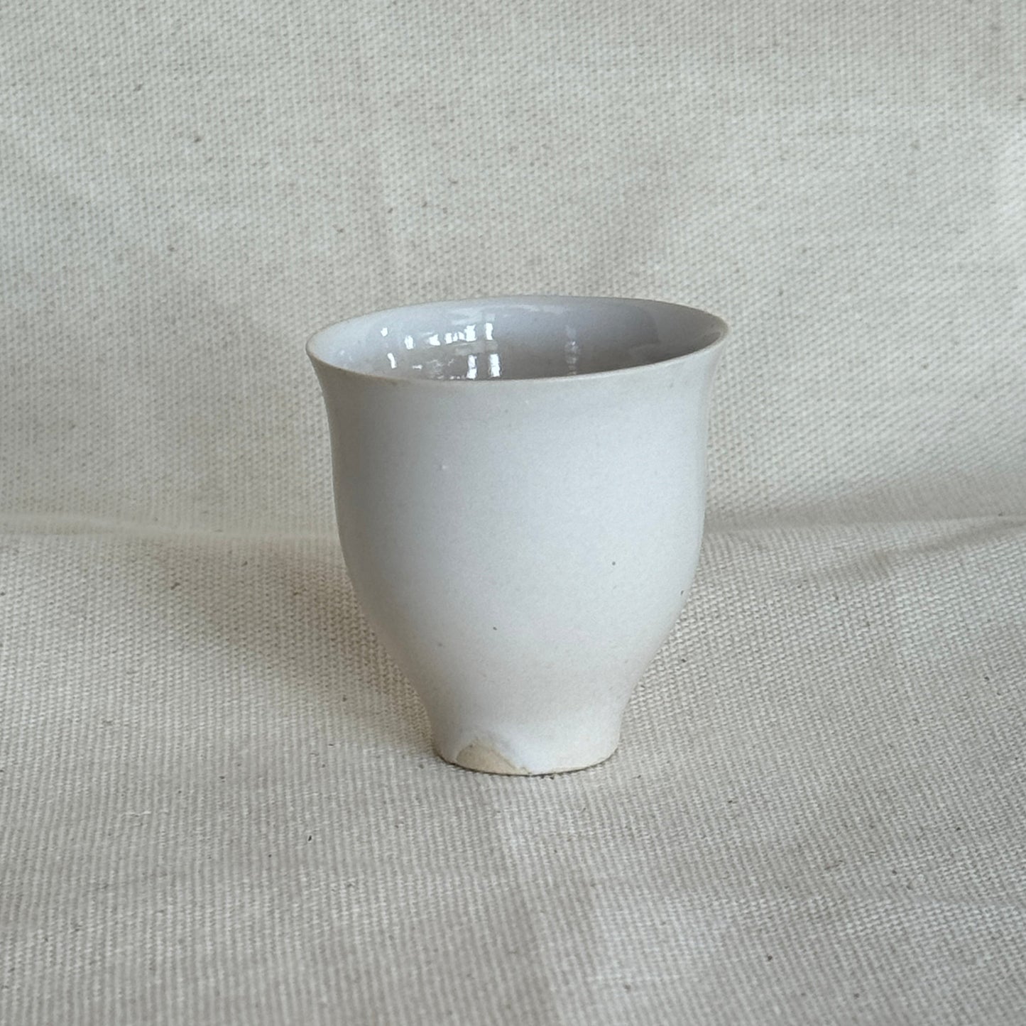 White ceramic cup on a textured beige fabric background