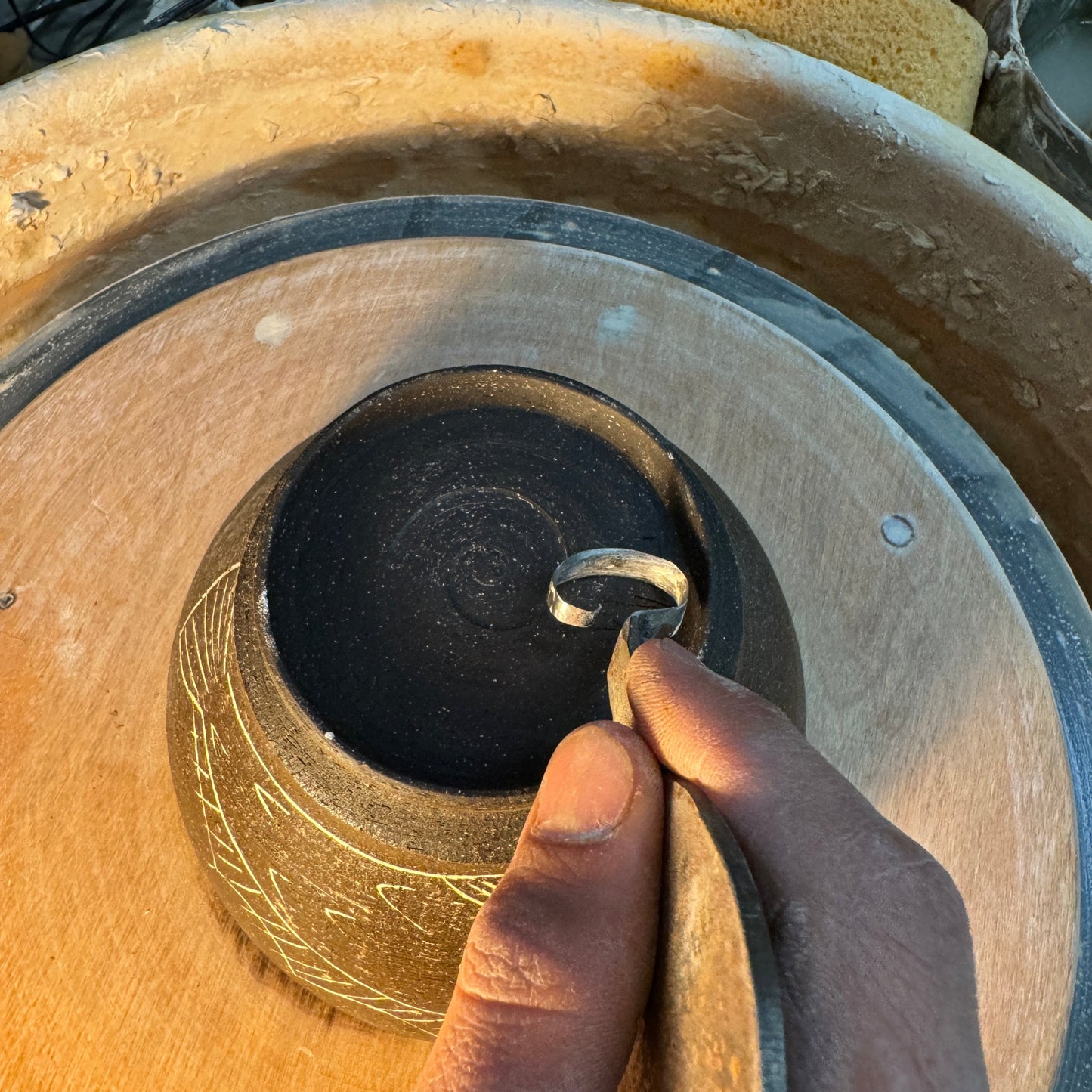 Hand holding a pottery trimming tool