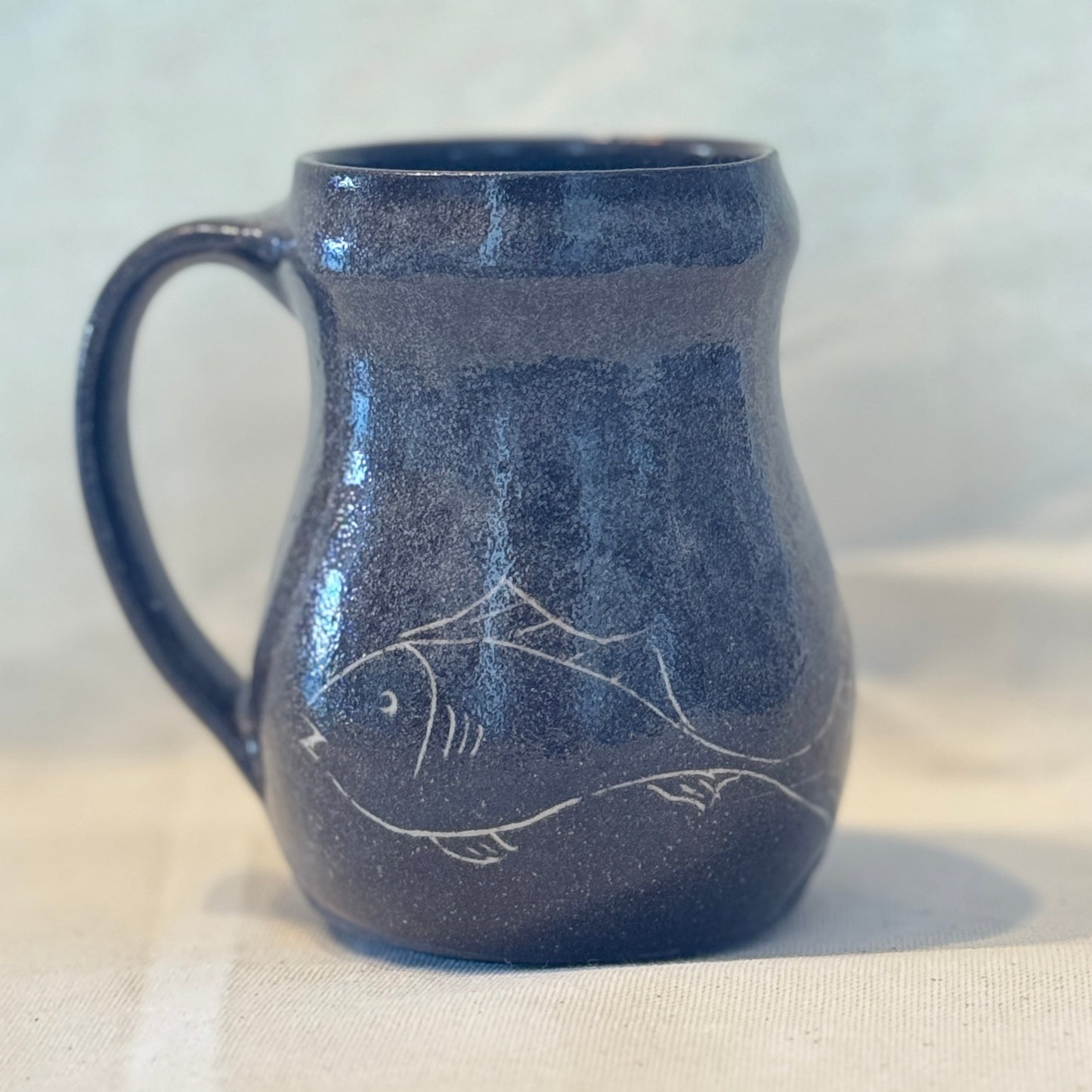 Brown ceramic mug with fish design on a white background