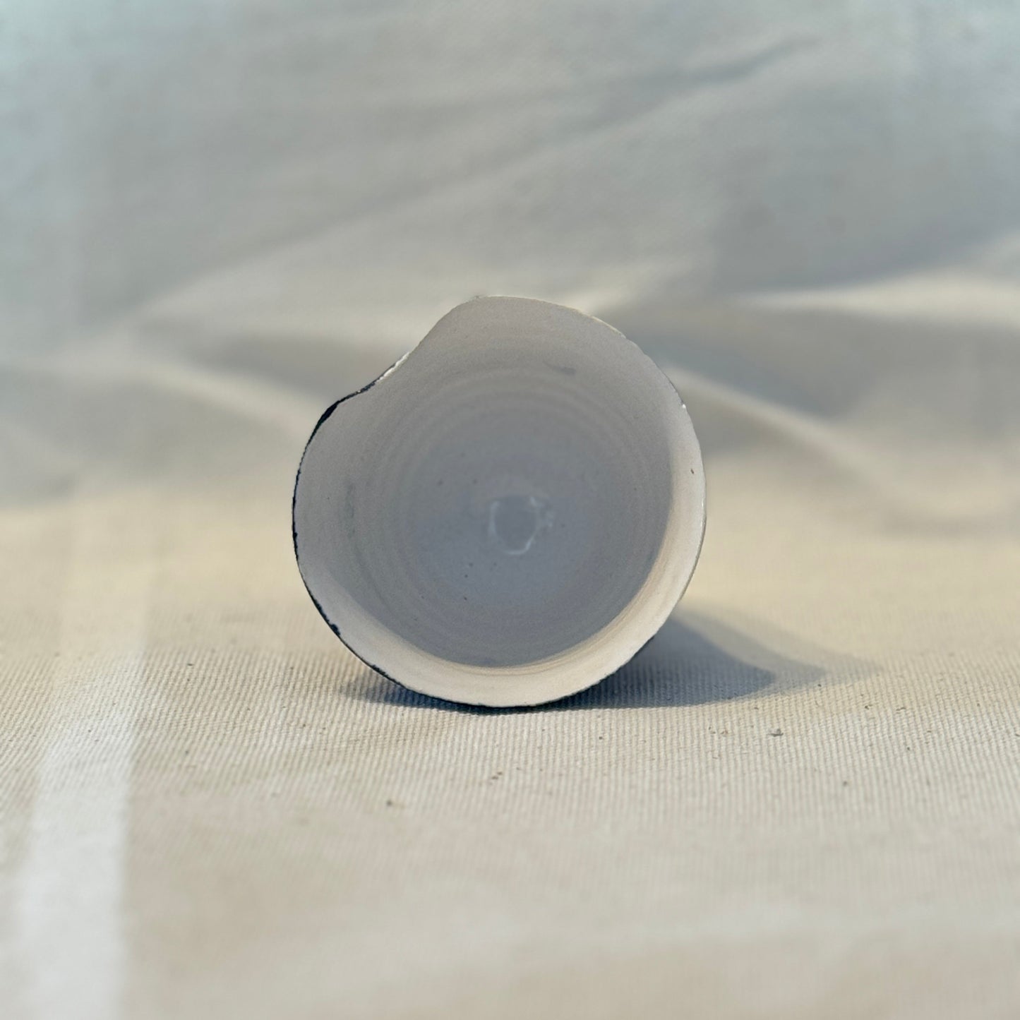 White cylindrical object on a textured beige surface with a light gray background