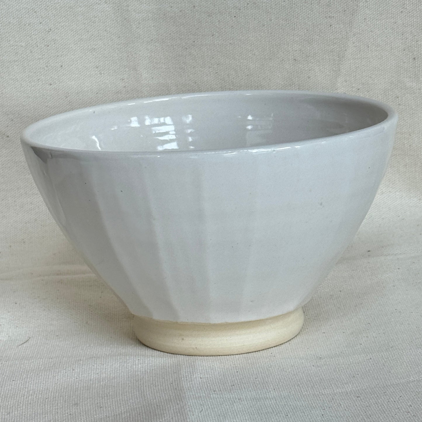 White ceramic bowl on a light gray fabric background