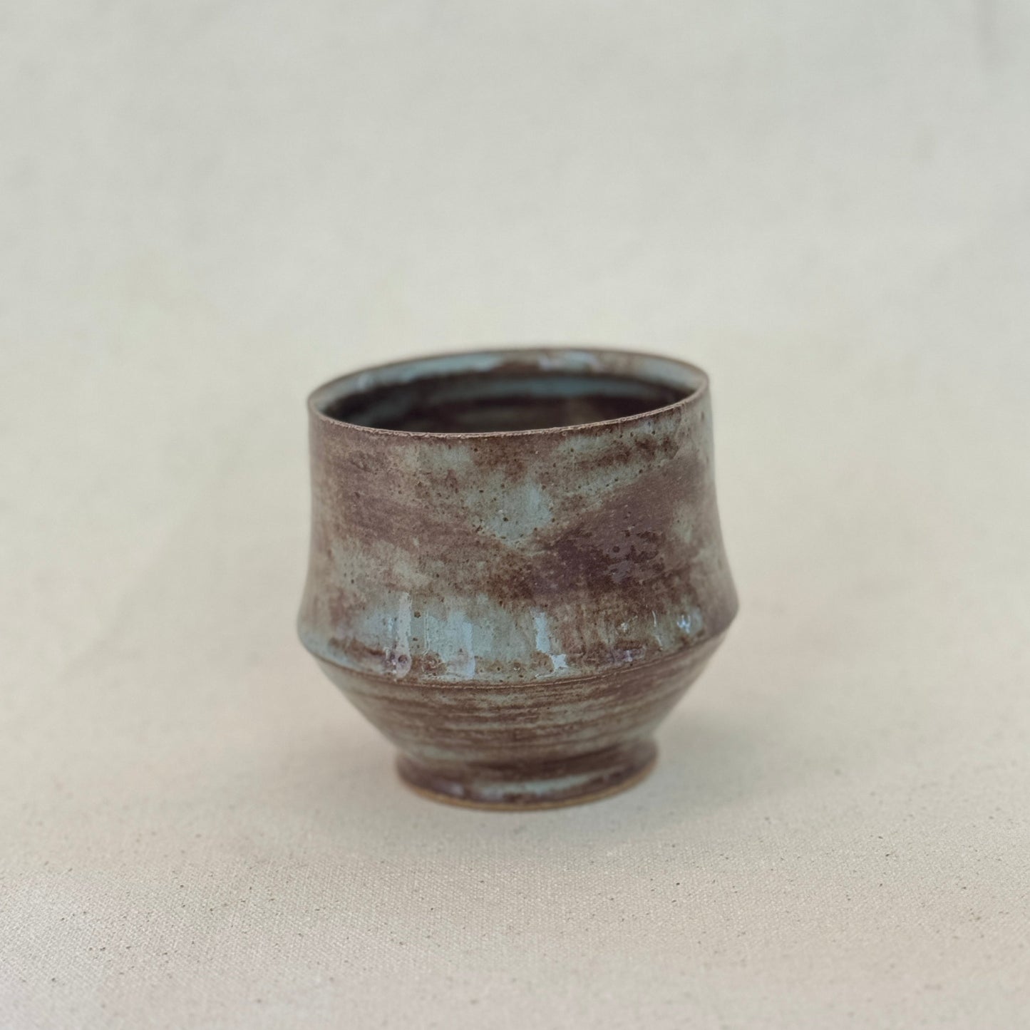 Ceramic cup with a textured surface on a light gray background