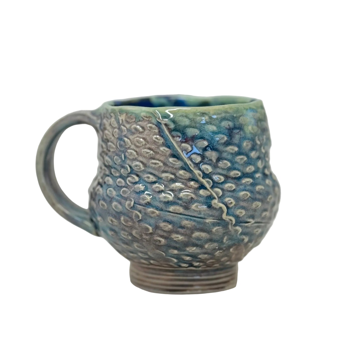 Handmade ceramic mug with textured surface on a white background