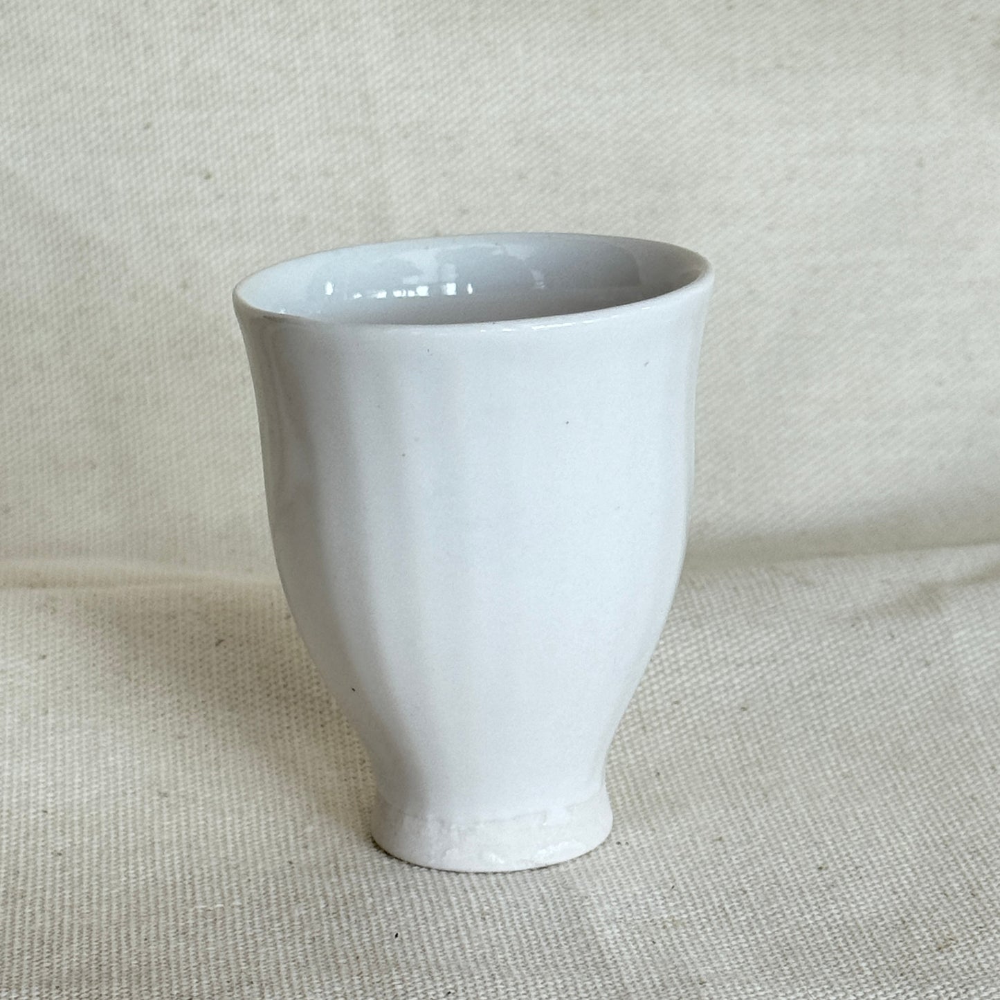 White ceramic cup on a beige fabric background