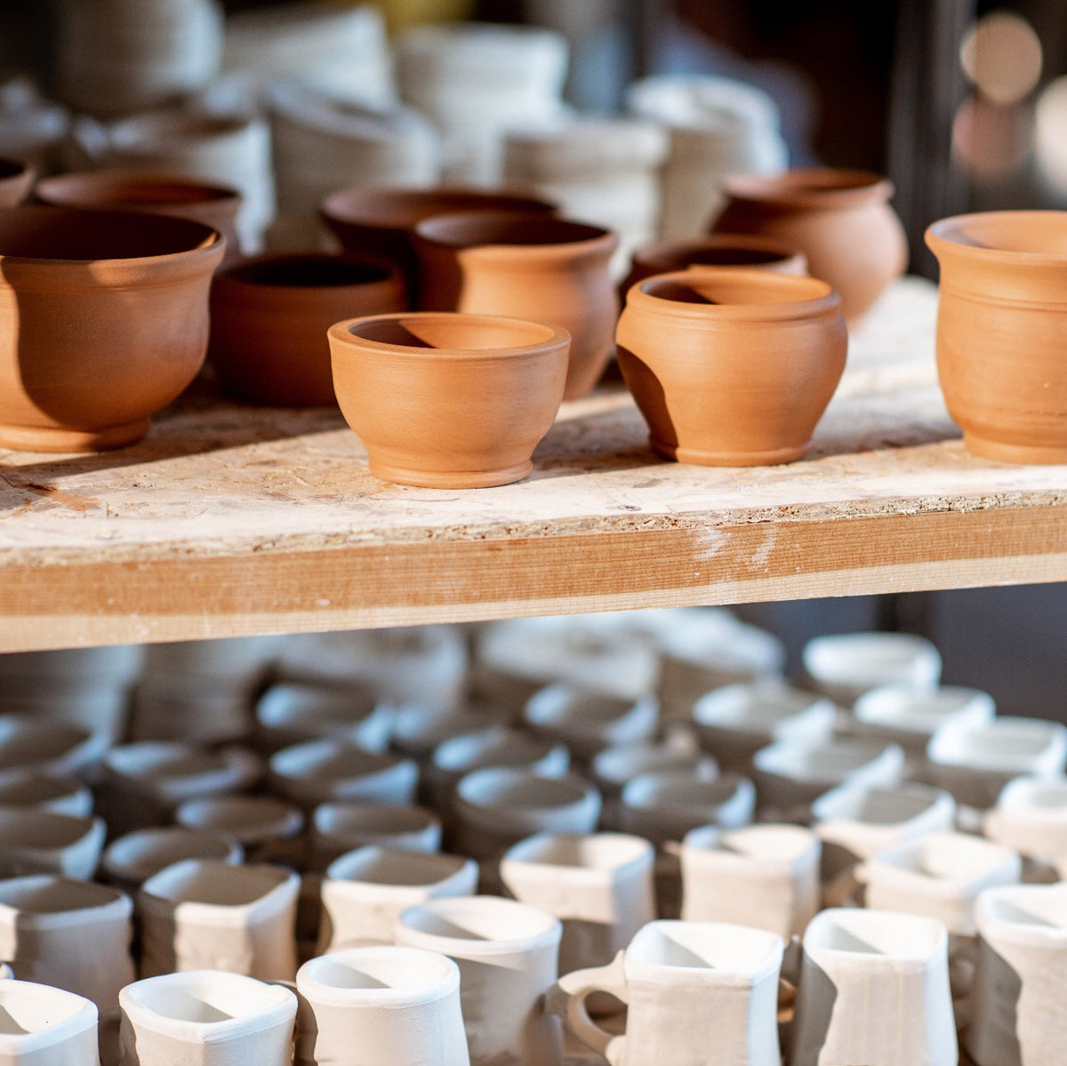 Collection of ceramic pots on a wooden shelf with a blurred background