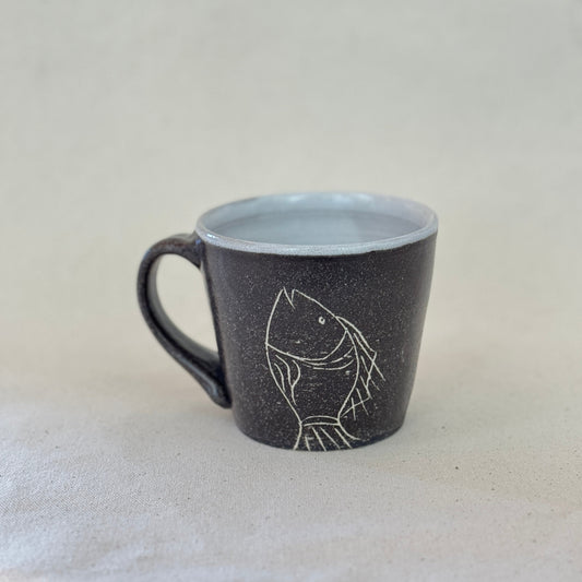 Black mug with a white fish design on a light gray background