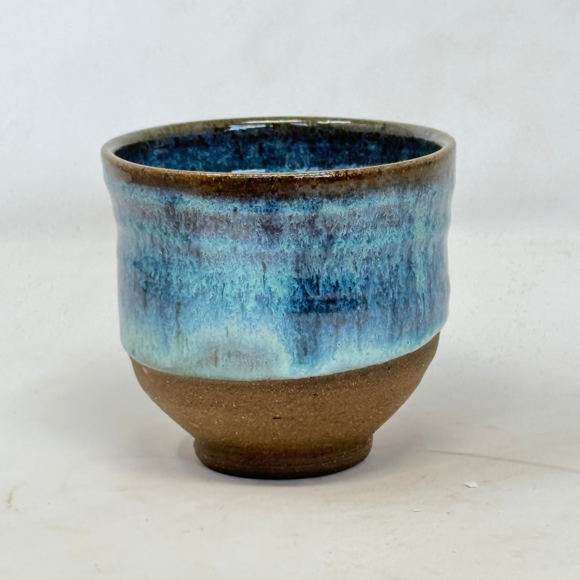 Ceramic cup with blue and brown glaze on a white background