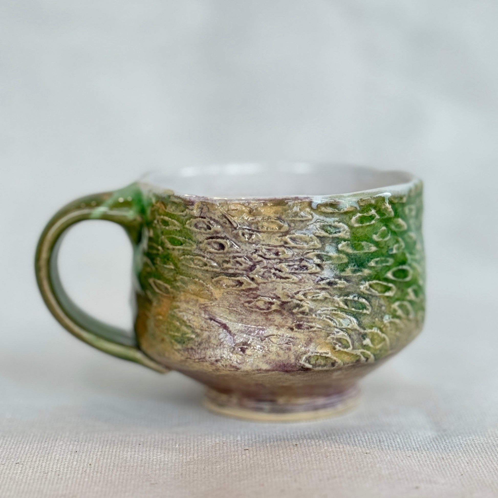 Ceramic mug with green and brown glaze on a white background