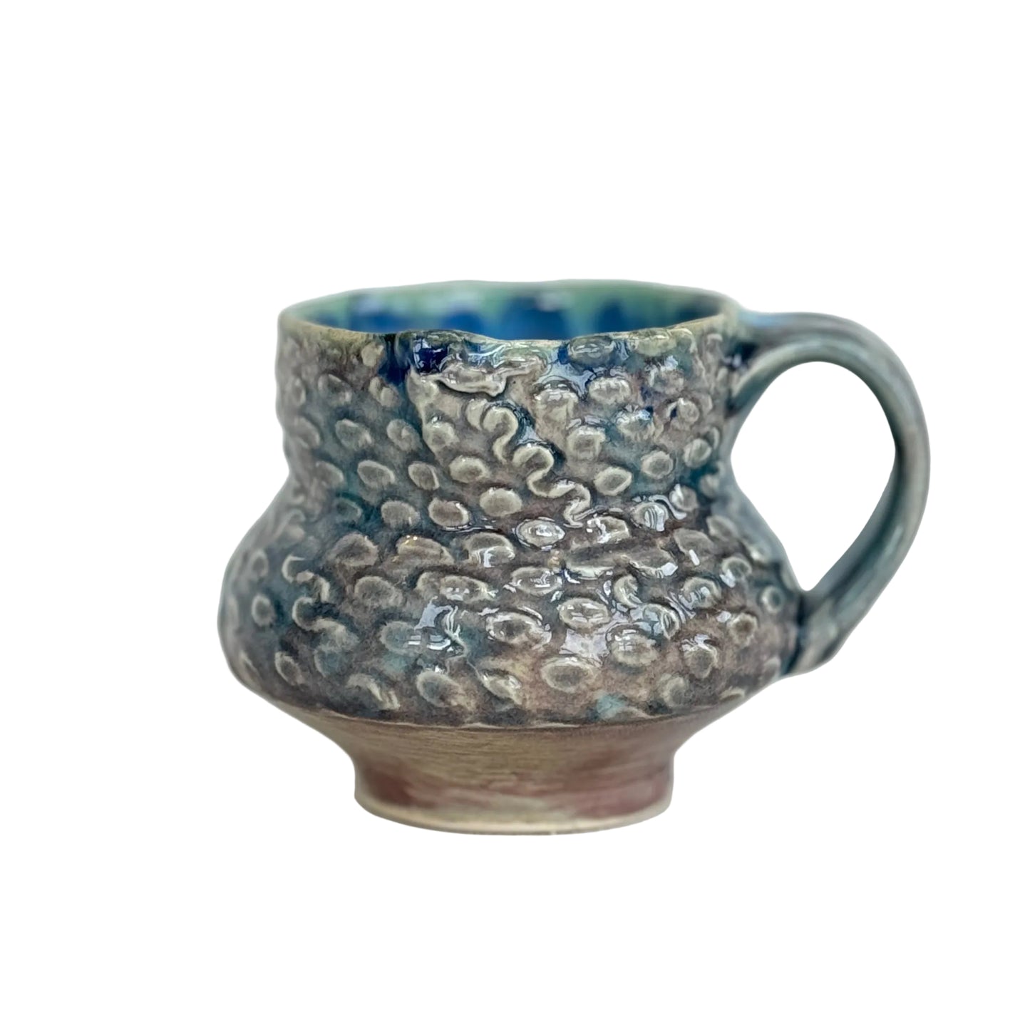 Handmade ceramic mug with textured surface on a light background