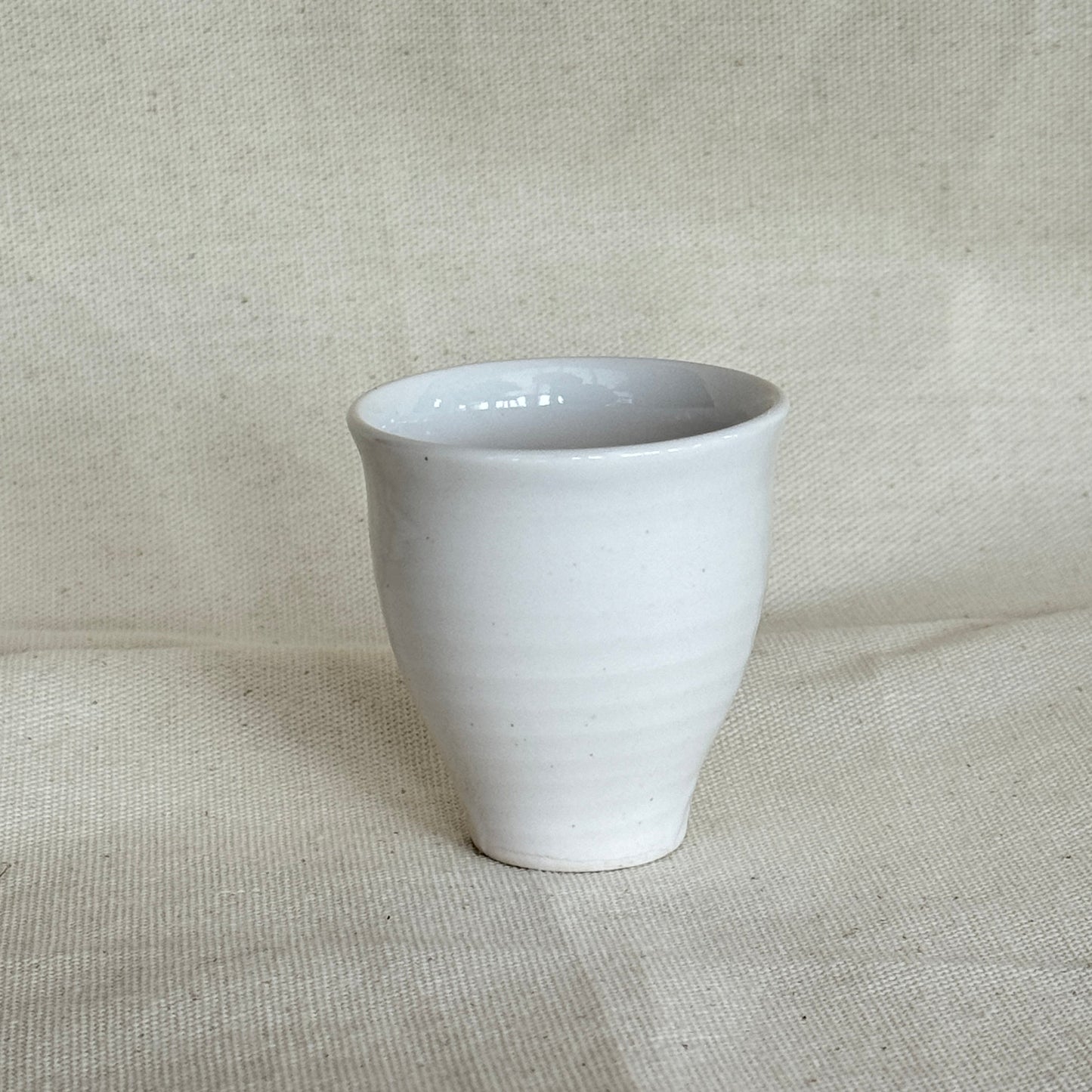 White ceramic cup on a textured beige fabric background