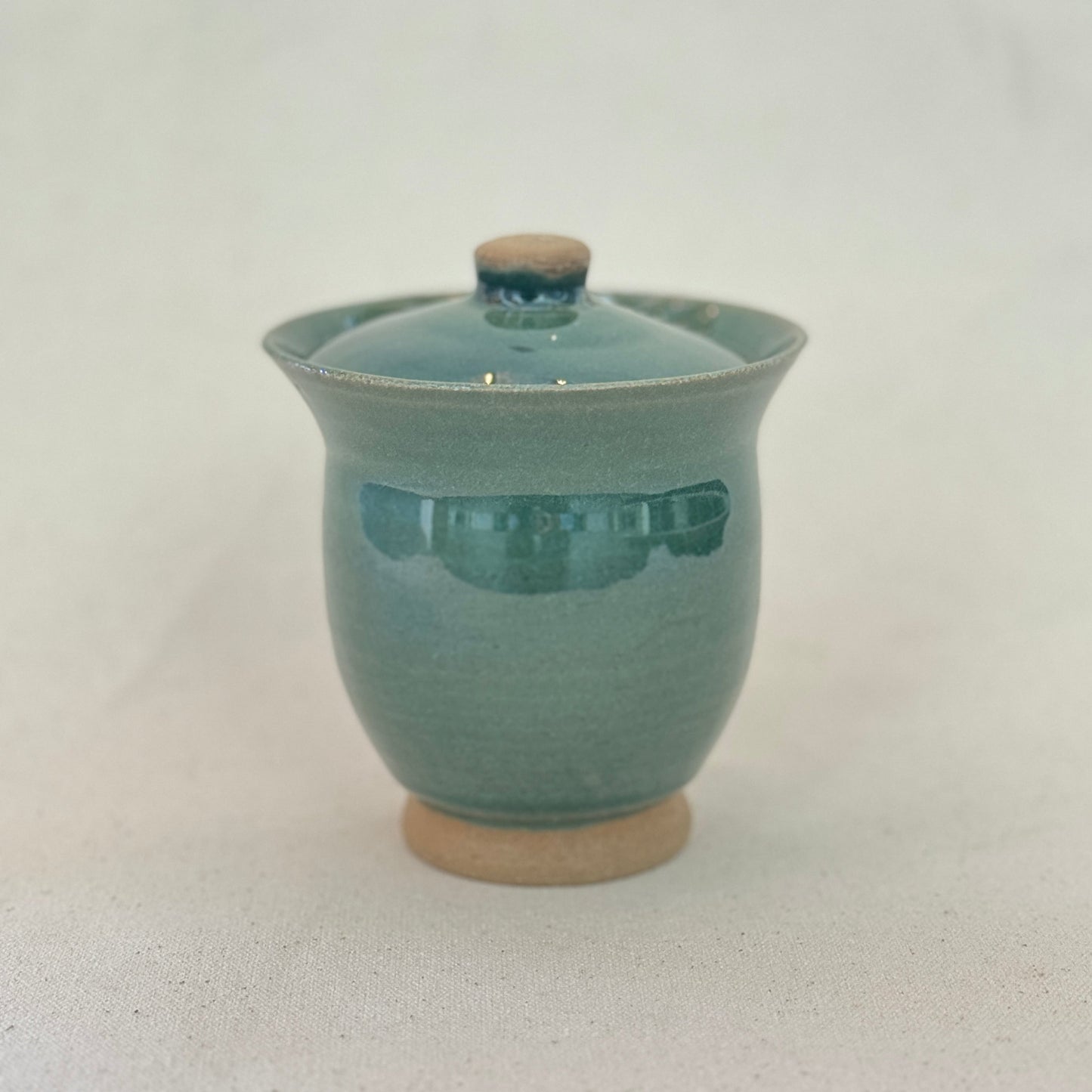 Teal ceramic cup with lid on a white background