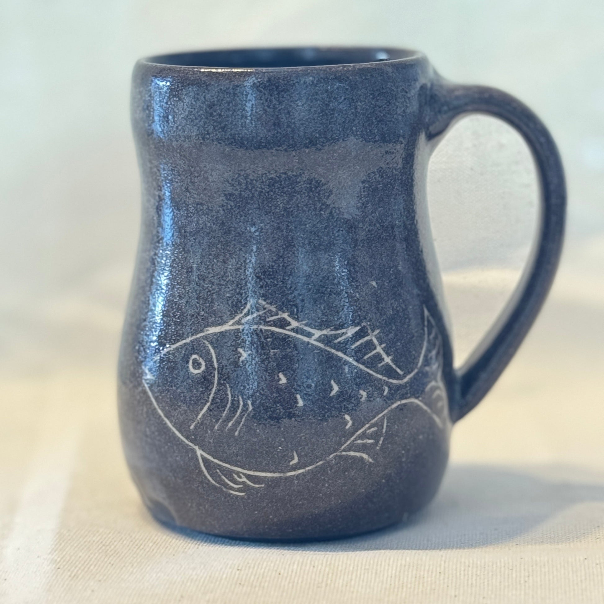 Blue ceramic mug with fish design on a white background