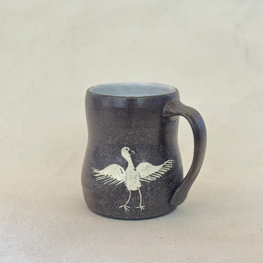 Black mug with a white bird design on a light gray background