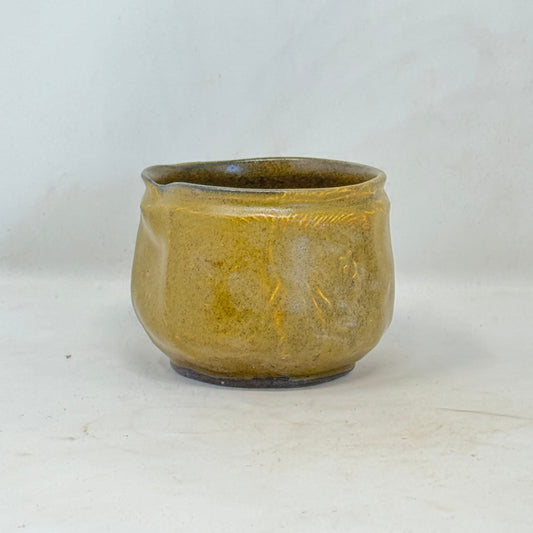 Small ceramic cup with a textured surface on a white background