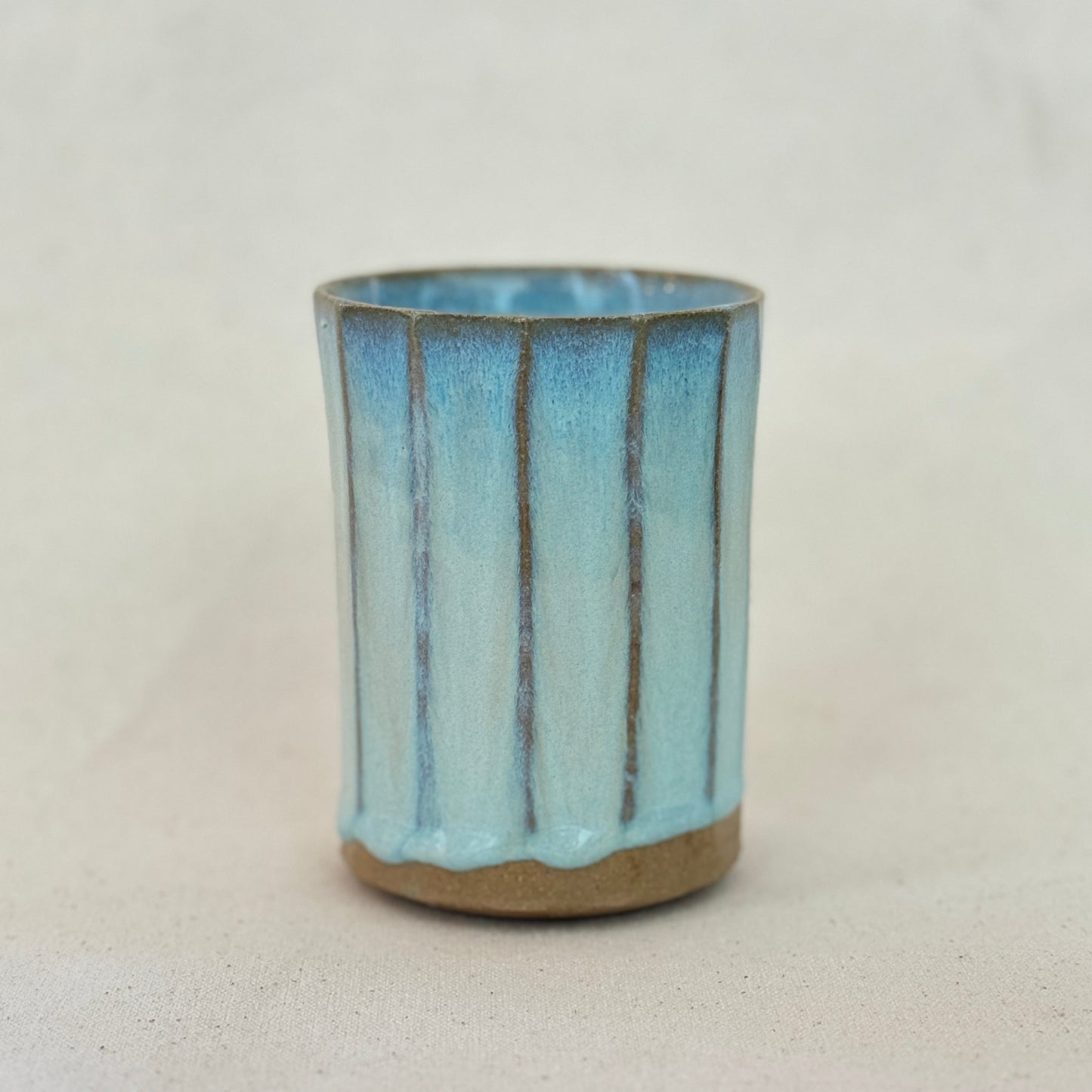 Ceramic cup with blue glaze on a white background