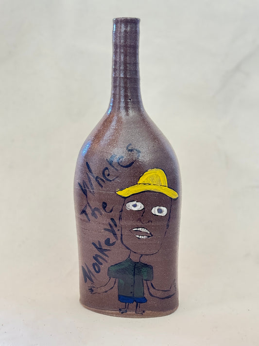Decorative bottle with a painted face and text on a plain background