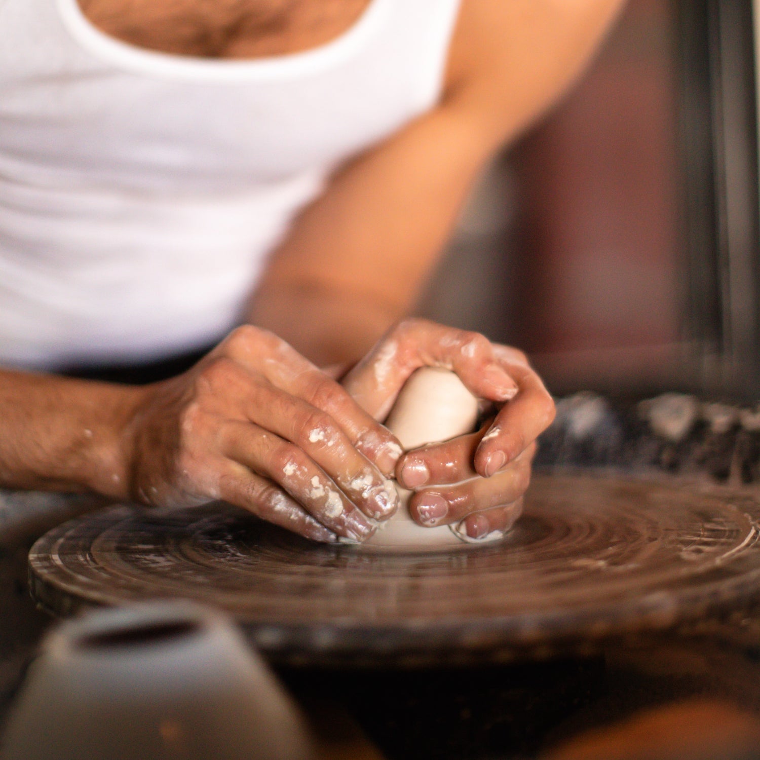 Person working with clay on a pottery wheel