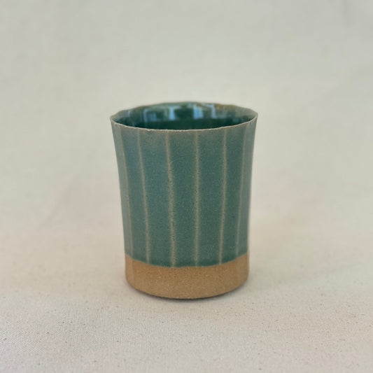 Green /blue ceramic cup with a textured pattern on a light background