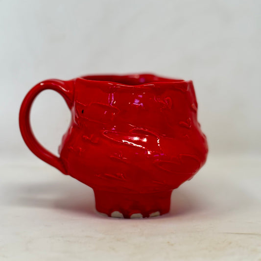 Red ceramic mug with textured design on a white background