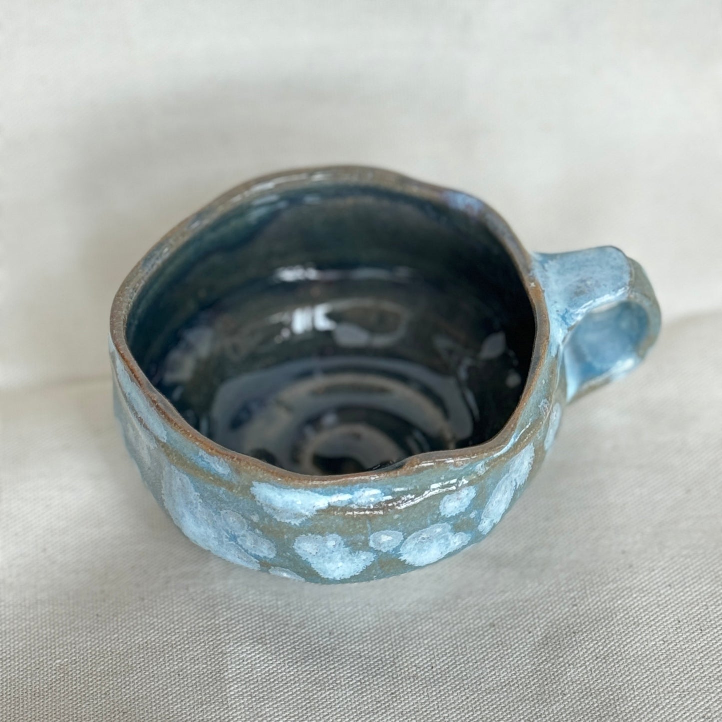 Blue ceramic cup with handle on a light gray background