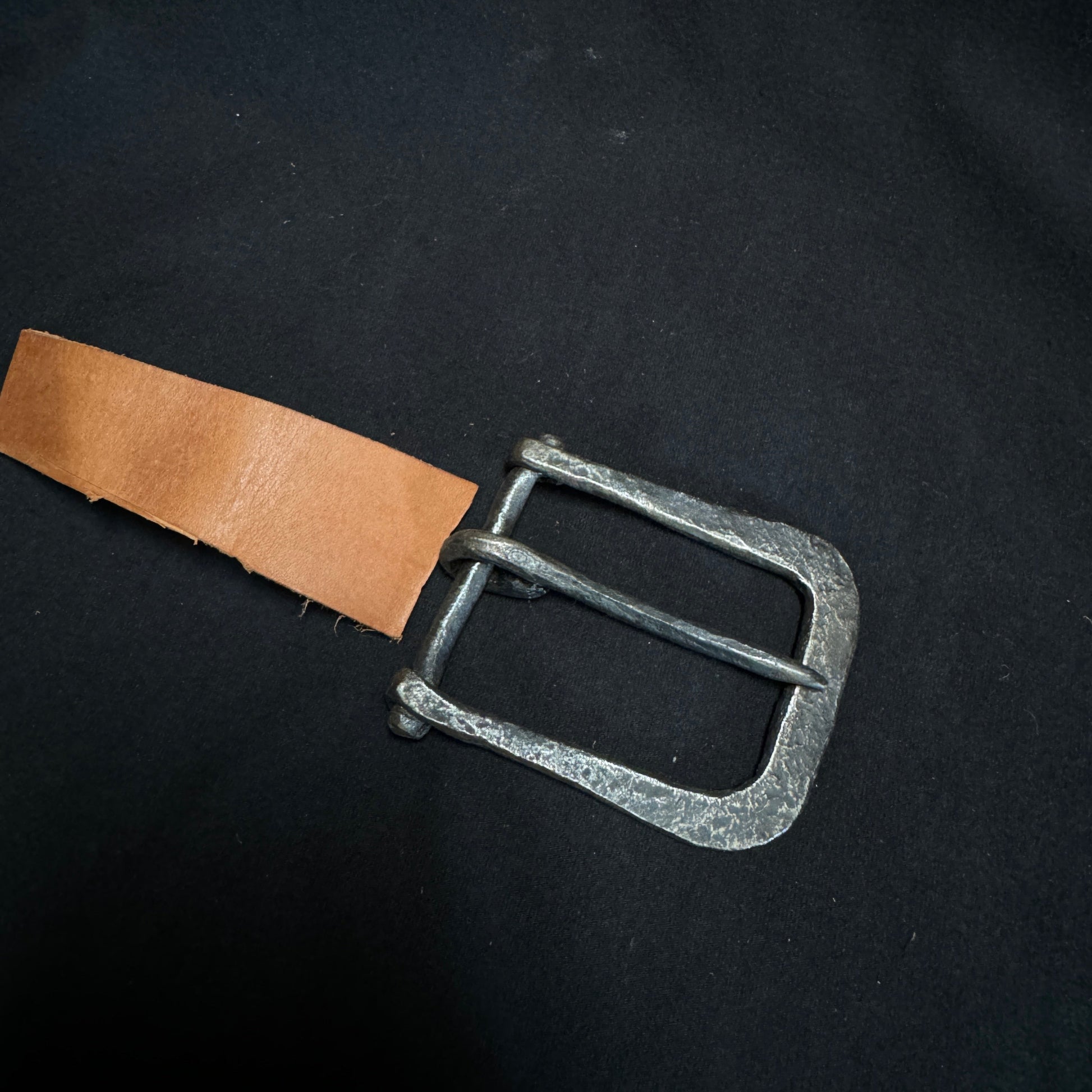 Belt buckle with leather strap on a black background