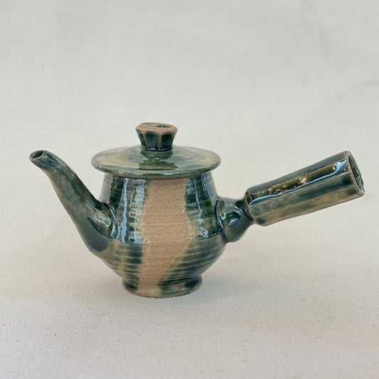 Ceramic teapot with a ribbed texture on a light gray background