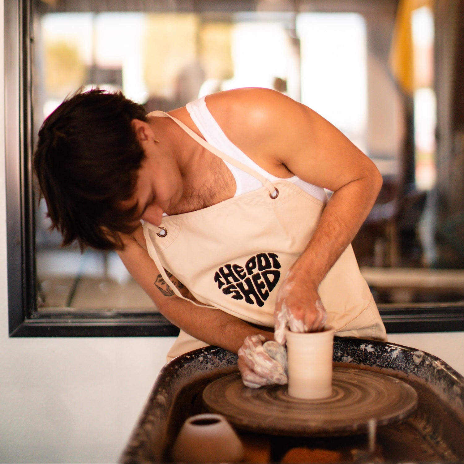Dax working with clay on a pottery wheel in a studio setting