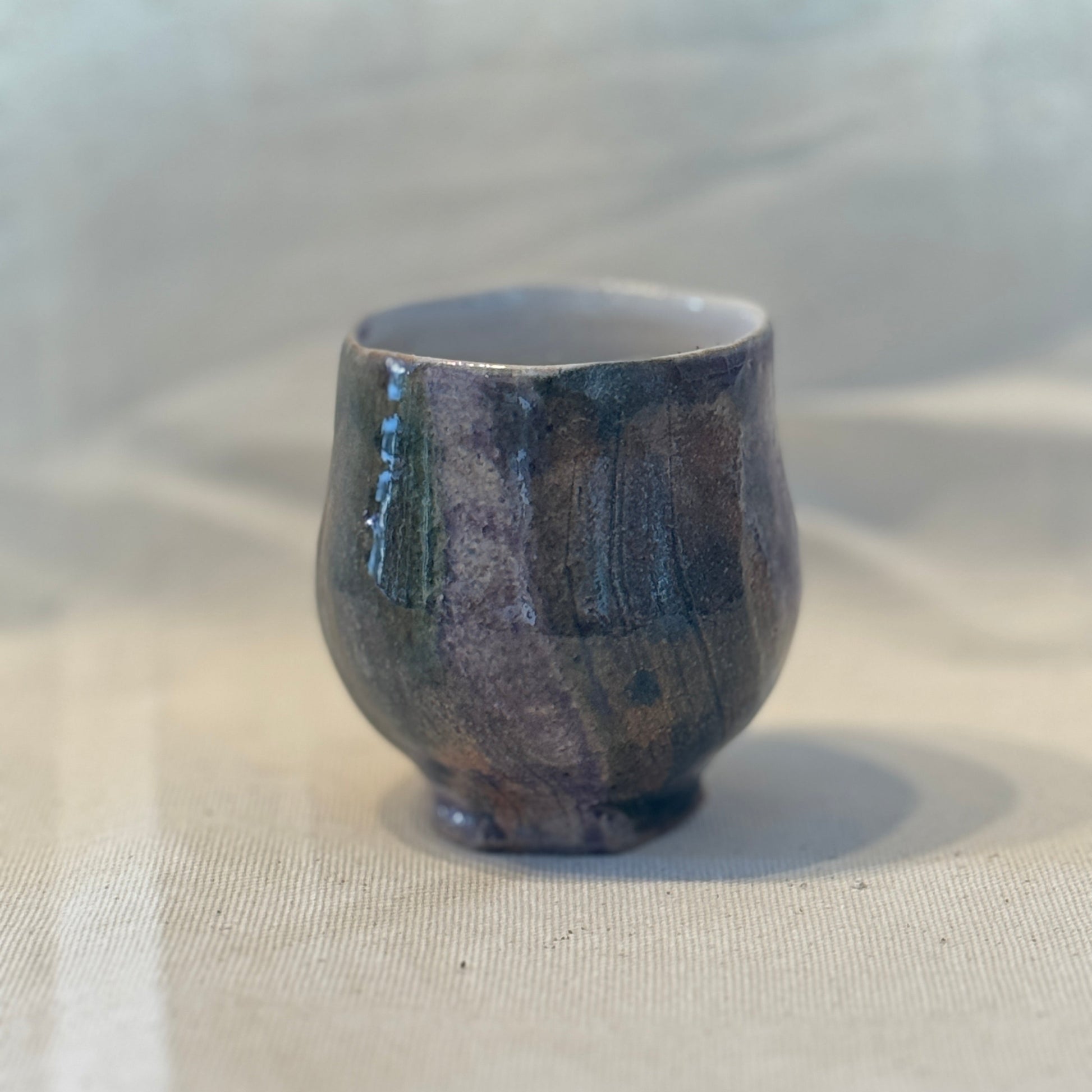 Small ceramic cup with a textured surface on a neutral background
