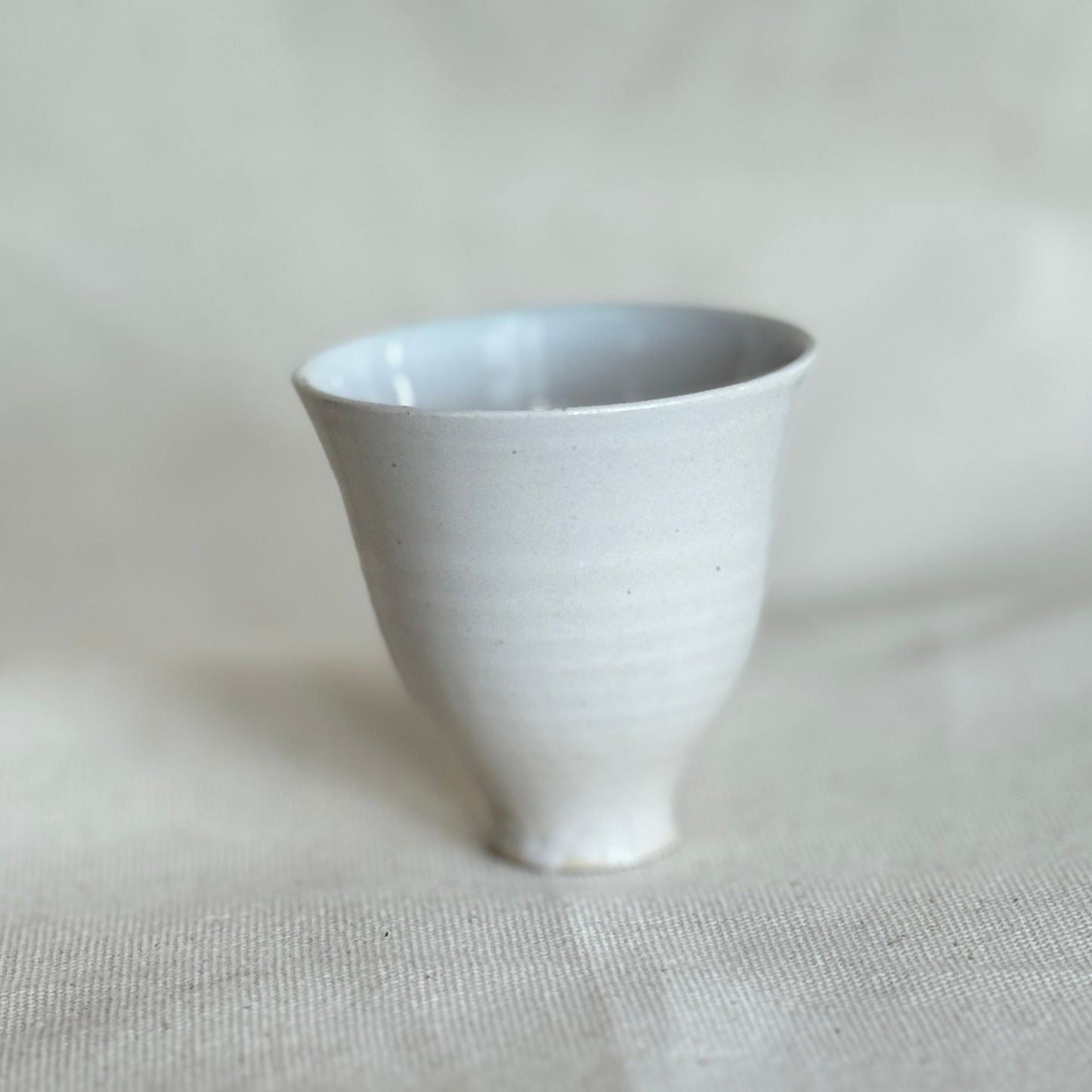 White ceramic cup on a light gray fabric surface