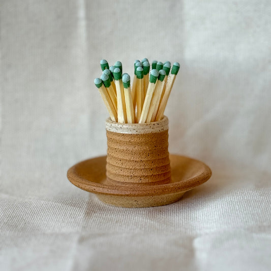 Matches in a ceramic holder on a light fabric background