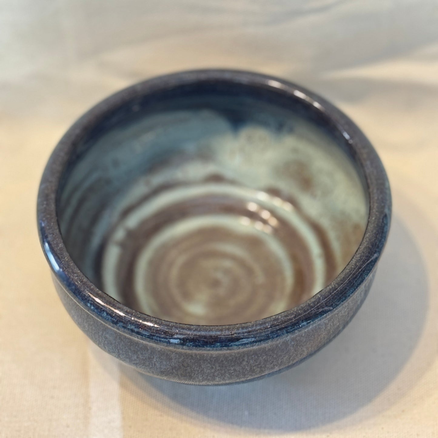 Ceramic bowl with blue exterior and swirling pattern on a white background