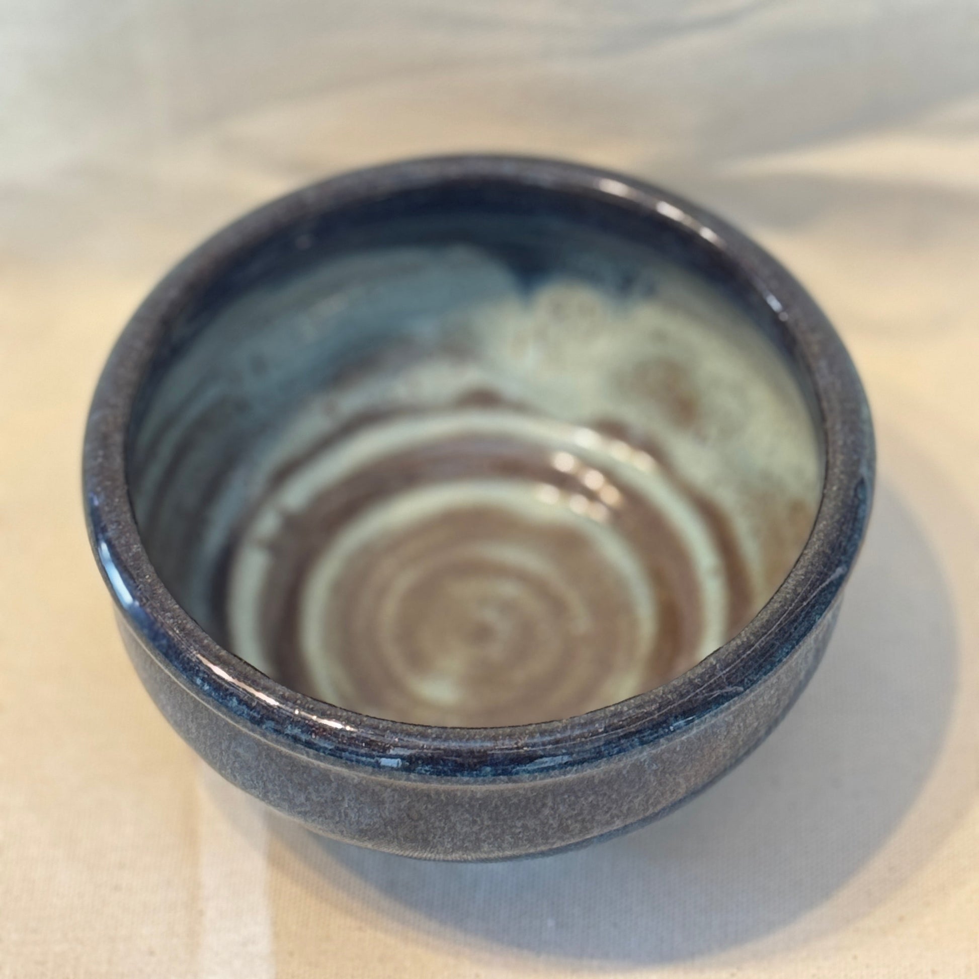 Ceramic bowl with blue exterior and swirling pattern on a white background