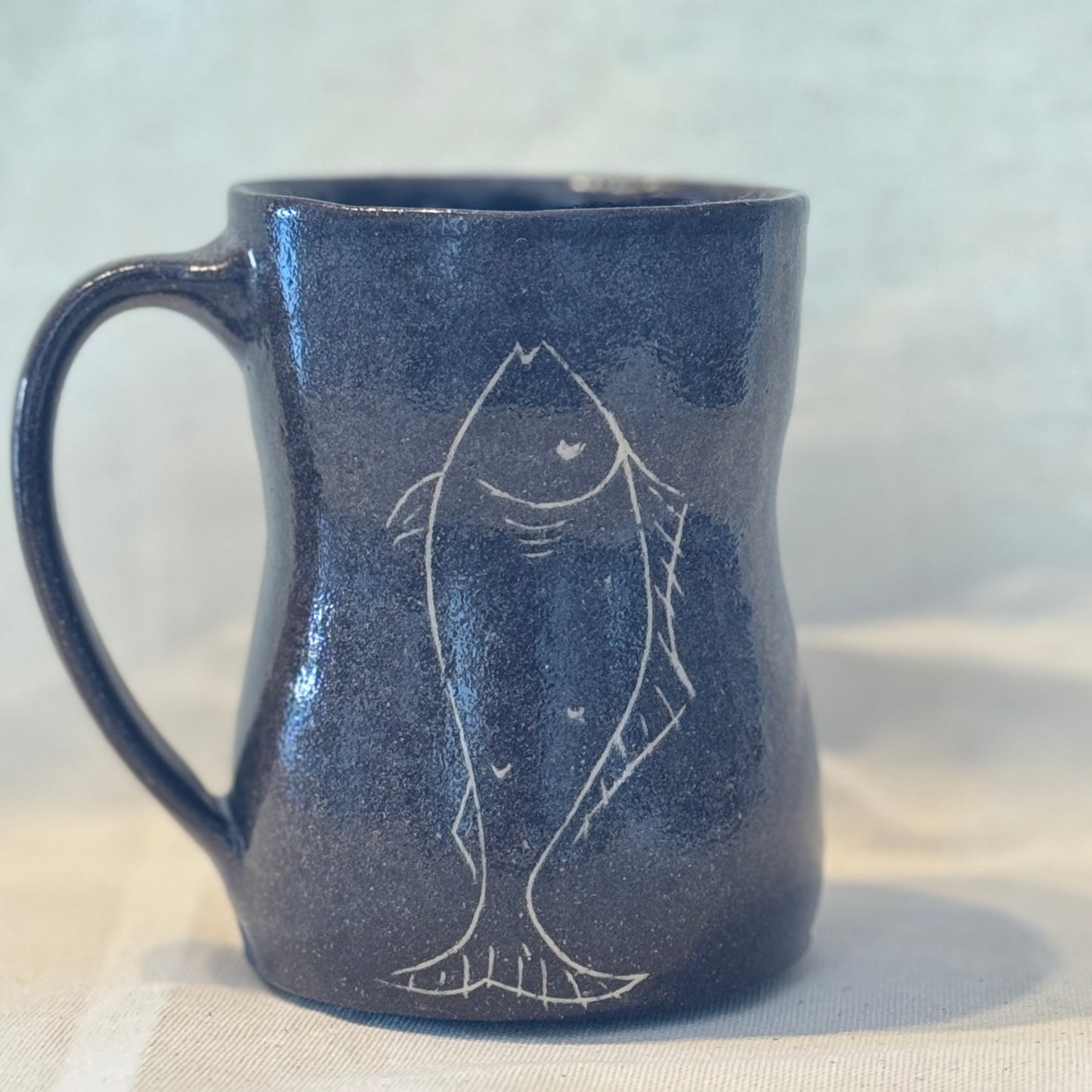 Blue ceramic mug with fish design on a white background