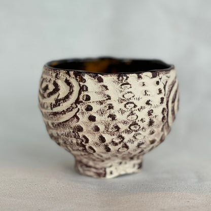 Ceramic cup with textured design on a light gray background