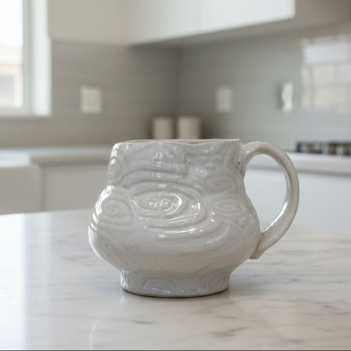 White ceramic mug with decorative patterns on a white background