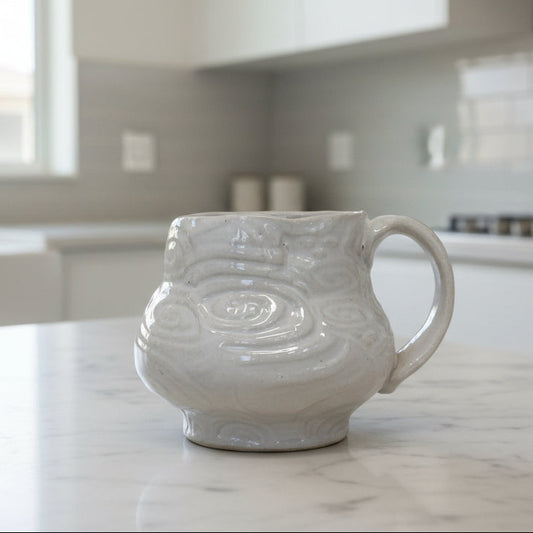 White ceramic mug with decorative patterns on a white background