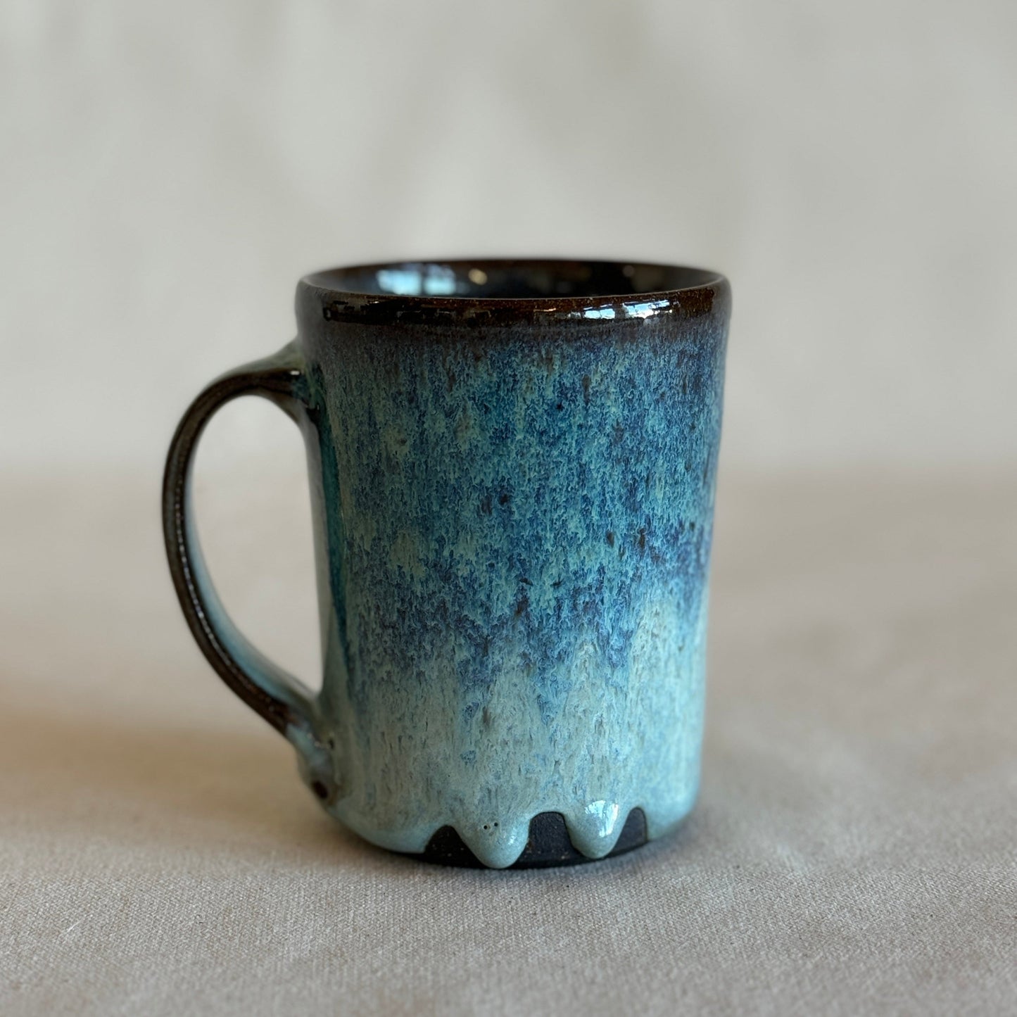 Blue ceramic mug with a black rim on a light gray background