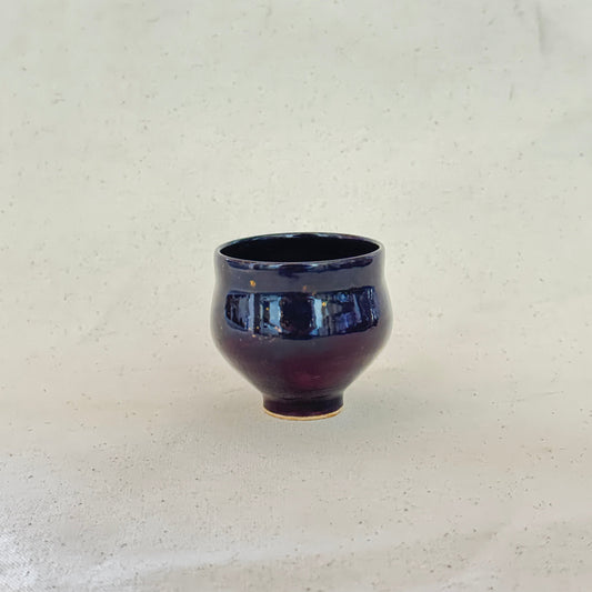 Ceramic cup with blue interior on a textured white surface