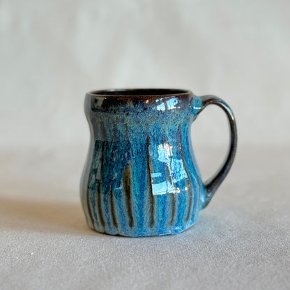 Blue ceramic mug with black interior on a light gray background
