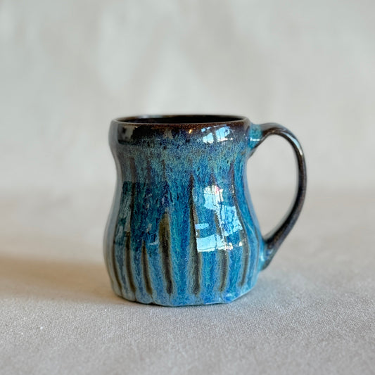 Blue ceramic mug with black interior on a light gray background