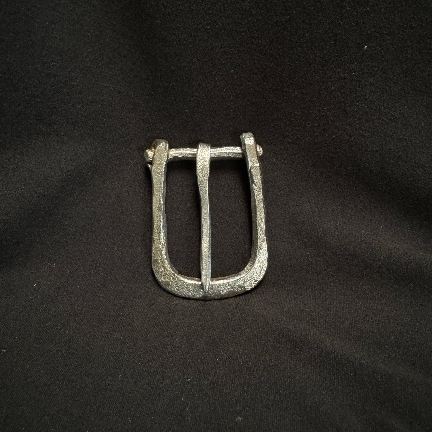 Silver belt buckle on a black fabric background