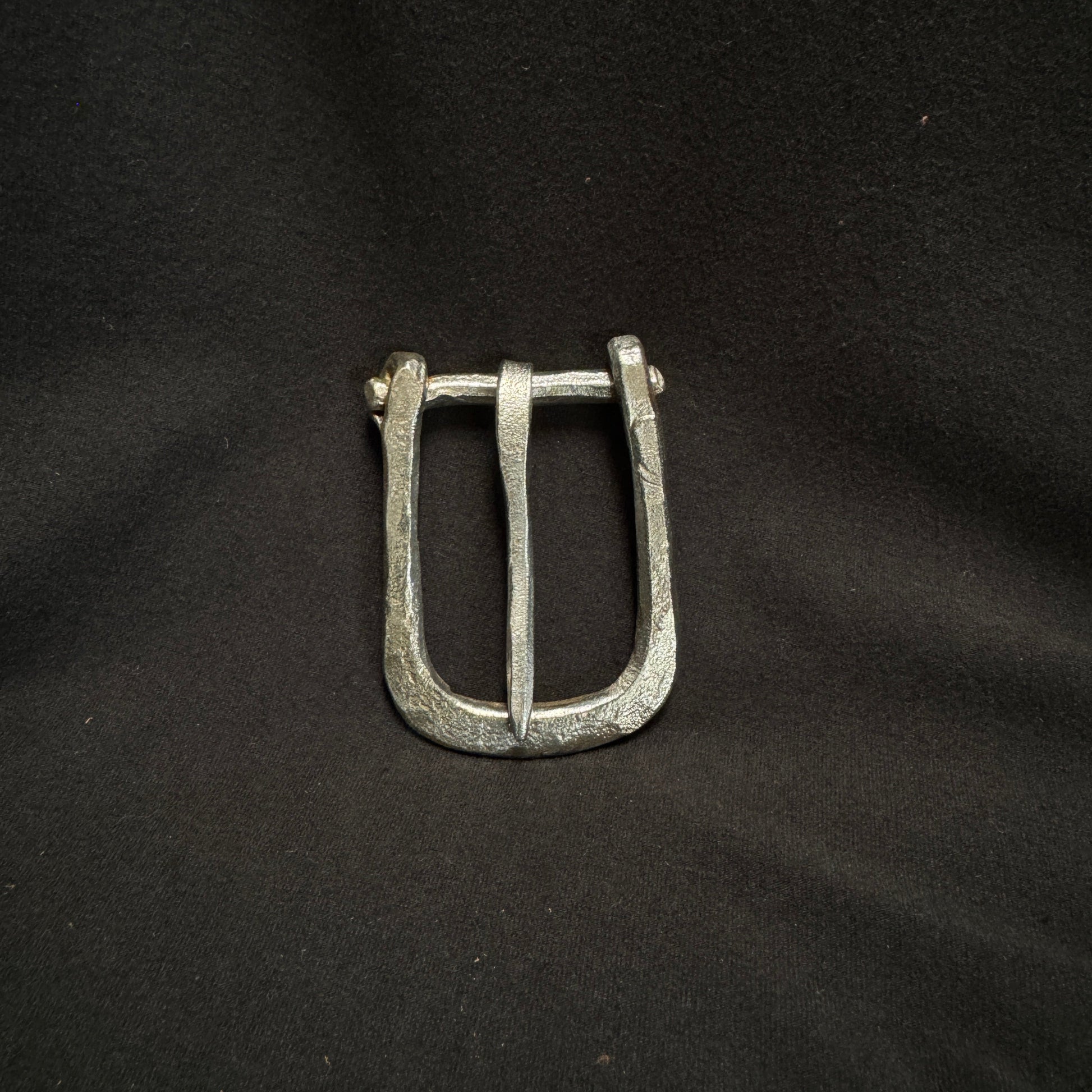 Silver belt buckle on a black fabric background