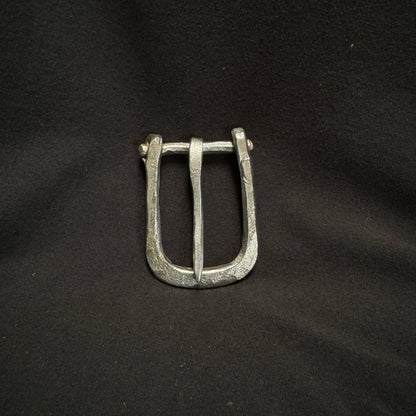 Silver belt buckle on a black fabric background