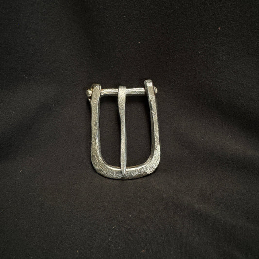 Silver belt buckle on a black fabric background